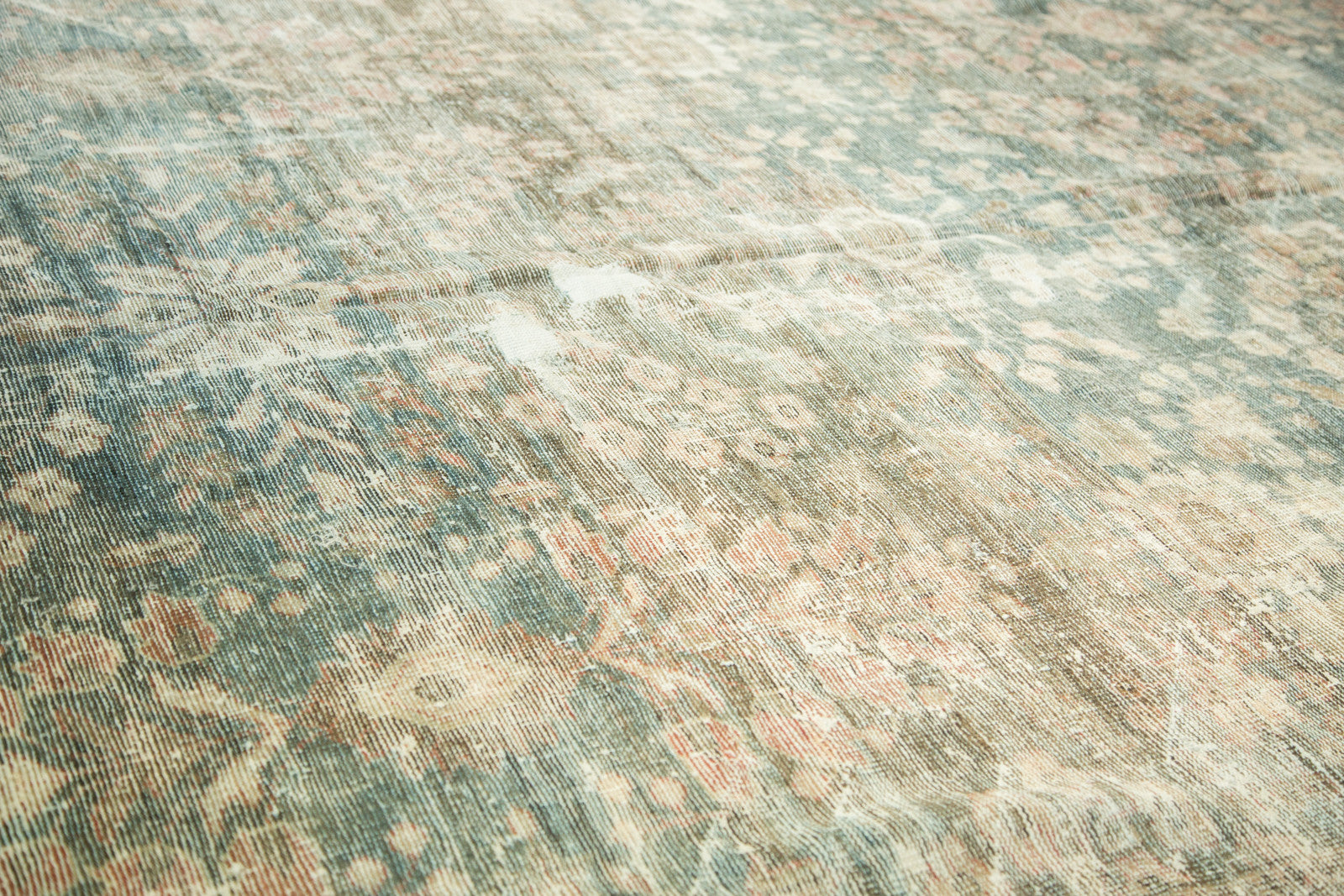 Worn pile texture of distressed Mahal carpet, with faded dusty teal and pomegranate red floral motifs.